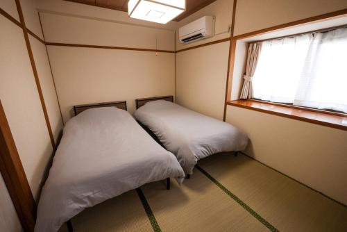 two beds in a small room with a window at たびんちゅの宿 in Toyama