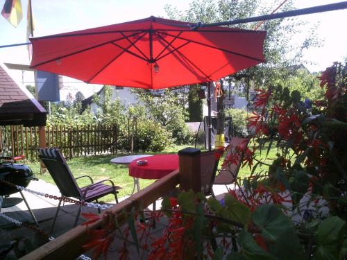 a red umbrella over a table and chairs at Wannenhof Romantik in Bernau im Schwarzwald