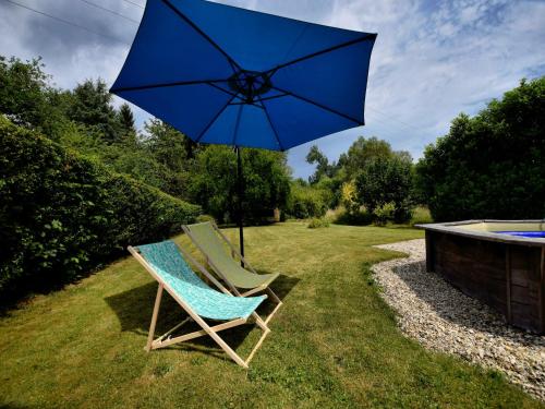 a pair of chairs and an umbrella in the grass at Holiday Home in Virton with swimming pool in Virton