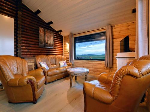 TennevilleにあるQuiet chalet with panoramic view and fenced gardenの革製の家具と大きな窓のあるリビングルーム