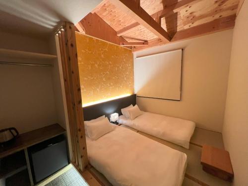 a small room with a bed and a wooden ceiling at おおさか城北 宿福 in Osaka