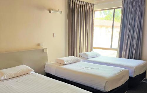three beds in a room with a window at Sanno Marracoonda Perth Airport Hotel in Perth
