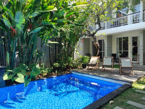 a swimming pool in a yard with chairs and plants at Sapo Jimbaran Bali in Jimbaran