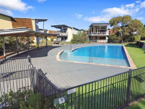 a swimming pool with a wooden deck next to a house at South Shores Villa 12 in Normanville