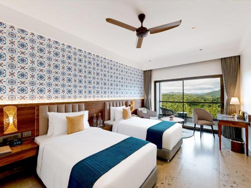 two beds in a hotel room with a ceiling fan at Gateway Goa, Palolem in Palolem