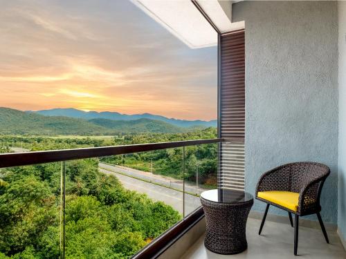 a balcony with a chair and a view of the mountains at Gateway Goa, Palolem in Palolem