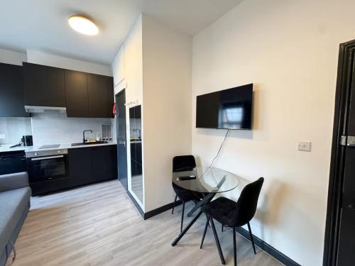 a kitchen with a glass table and black chairs at Golders Green Studios in London
