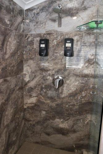 a bathroom with a shower with a stone wall at The Essenwood Collection in Durban
