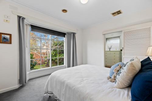 a bedroom with a bed and a large window at Hampton Spacious House & Pool in Melbourne