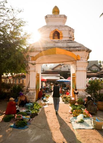 a woman walking through an outdoor market with fruits and vegetables at La Résidence Phou Vao in Luang Prabang