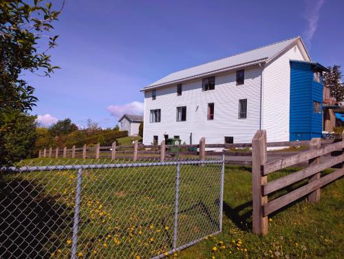 a white barn with a fence in front of it at Alert Bay, Spacious Executive Suite with Panoramic Ocean Views in Alert Bay