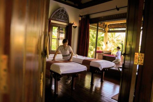 a man is making beds in a room at La Résidence Phou Vao in Luang Prabang
