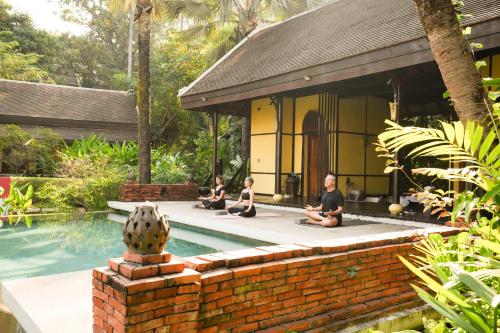 a group of people sitting around a swimming pool at La Résidence Phou Vao in Luang Prabang