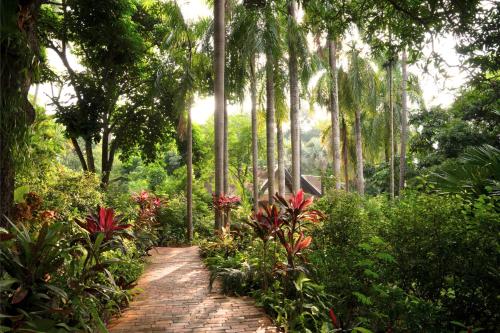 a brick path in a garden with flowers and trees at La Résidence Phou Vao in Luang Prabang