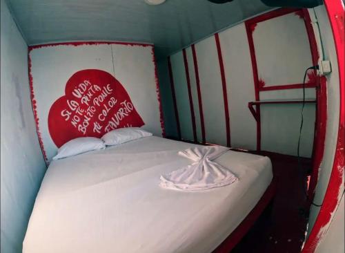 a small room with a bed with a heart pillow at Hostel bunker Peruano in Playa Blanca
