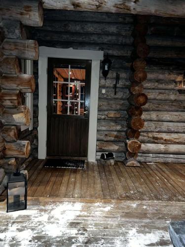 a cat sitting in front of a door in a log cabin at Aurora Bliss Cabin Retreat in Kilpisjärvi