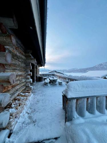 a snow covered porch of a log cabin with snow at Aurora Bliss Cabin Retreat in Kilpisjärvi