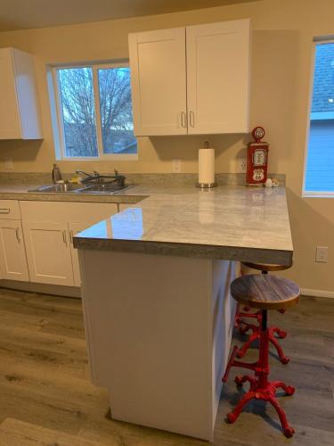 a kitchen with white cabinets and a bar with a stool at Authentic Remodeled Taber Street Railroad House in Williams