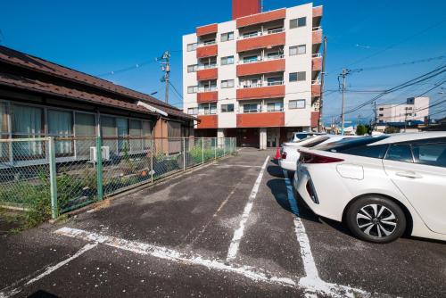 a parking lot with cars parked in front of a building at たびんちゅの宿 in Toyama