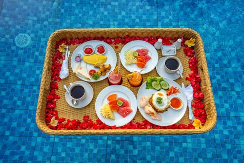 un vassoio di cibo con piatti di cibo in una piscina di Bela's Vana Villa Ubud by Dhananjaya Hospitality a Tampaksiring