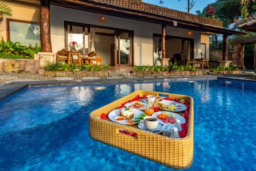 un vassoio di cibo seduto al centro della piscina di Bela's Vana Villa Ubud by Dhananjaya Hospitality a Tampaksiring
