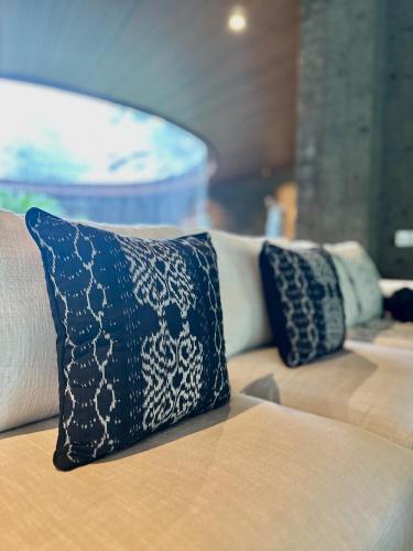 a couch with two blue and white pillows on it at Beautiful Round Villa in Payangan in Payangan