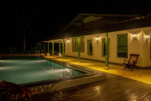 a swimming pool in front of a house at night at Sinharaja River Lodge in Nikawatawana