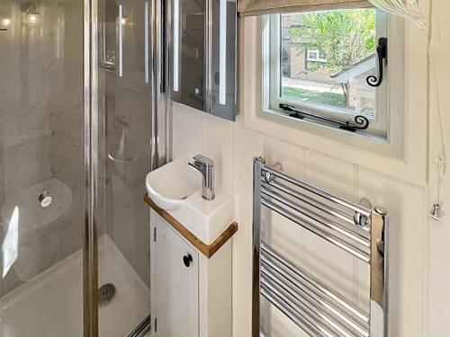 a bathroom with a sink and a shower at Helen's Shepherds Hut in Enford