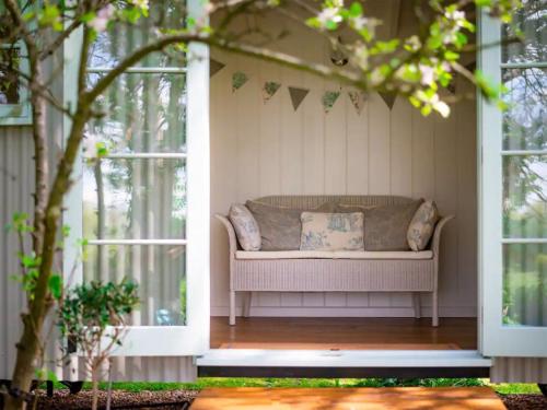 a couch on a porch with two windows at Helen's Shepherds Hut in Enford