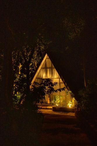 a house lit up at night with lights around it at Sinharaja River Lodge in Nikawatawana