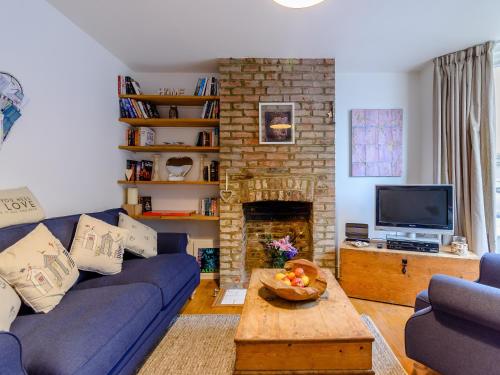 a living room with a blue couch and a fireplace at Anchor Cottage in Whitstable