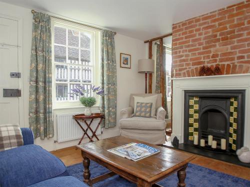 a living room with a couch and a fireplace at Pilgrim Cottage in Hollingbourne
