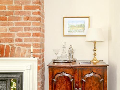 a lamp on a wooden cabinet next to a fireplace at Pilgrim Cottage in Hollingbourne