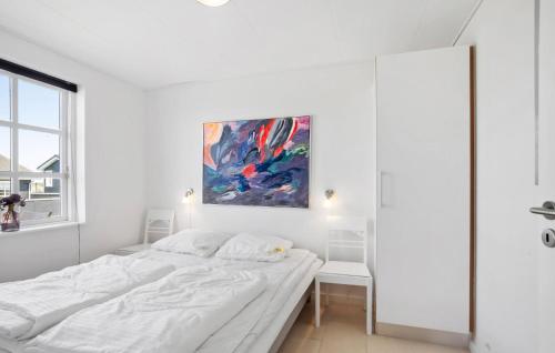 a white bedroom with a bed and a painting on the wall at Holiday Home Strandgårdsvej Bagenkop Denm in Bagenkop