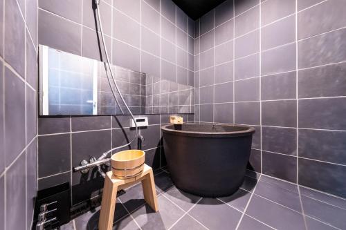 a bathroom with a large tub and a stool at 光 和風お風呂を楽しむお宿 usjまで電車で1分 駐車場付き ベッド6台 寝室3つ バスルーム2台 in Osaka