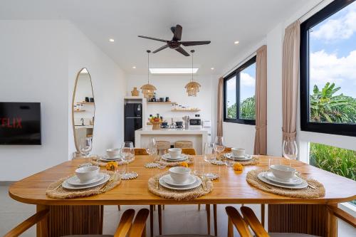 a dining room with a wooden table with glasses on it at Villa Romance in Tumbak Bayuh