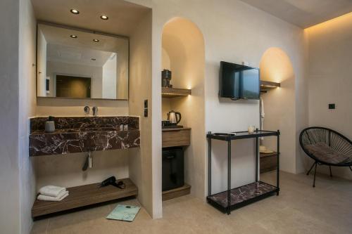 a bathroom with a sink and a mirror and a television at Ano Kampos Hotel in Faliraki