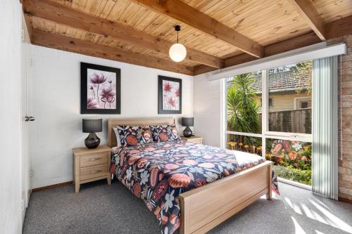 a bedroom with a bed and a large window at Bungunyah Apartments in Croydon