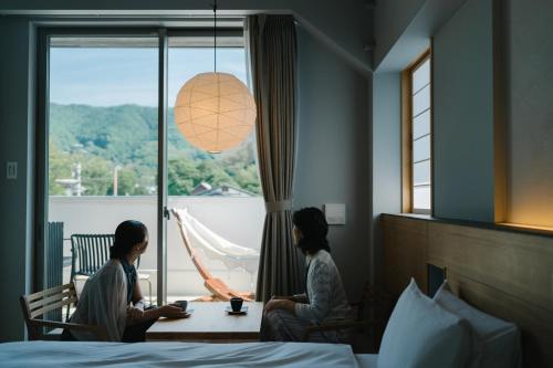 two women sitting at a table in a room with a window at ブランシエラ石舞台テラス Branchera Ishibutai Terrace in Asuka