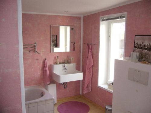 a pink bathroom with a sink and a bath tub at Ferienhaus in Waren an der Müritz in Waren