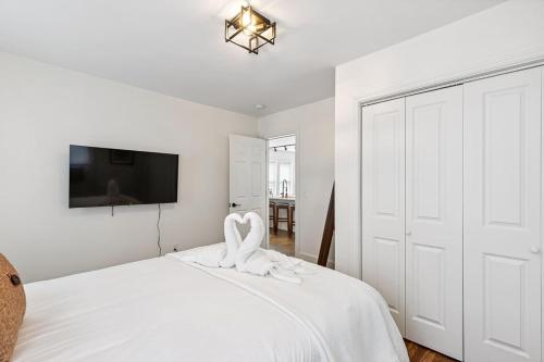 a white bedroom with a bed and a flat screen tv at Federal HILL PRIDE 1 - Ground-Floor Flat in Providence