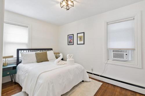 a white bedroom with a bed and two windows at Federal Hill PRIDE in Providence