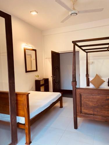 a bedroom with a wooden bed and a mirror at White Resort - 1 Min walk to the Beaches in Tangalle