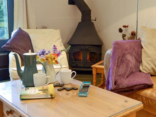 un soggiorno con tavolino e camino di Clematis Cottage a Holsworthy