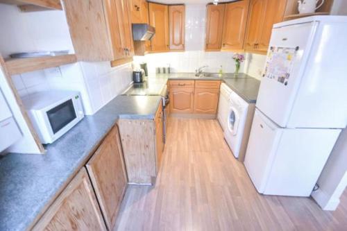 a kitchen with a white refrigerator and wooden cabinets at Seaside High Street Homely Hideaway in Dunbar