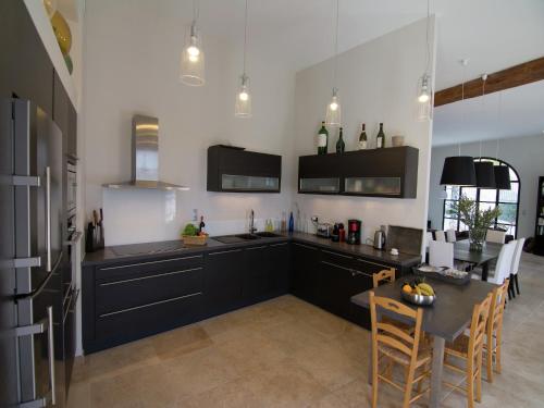 een keuken met zwarte kasten en een tafel met stoelen bij Holiday Home in Hérault with Pool in Campagnan