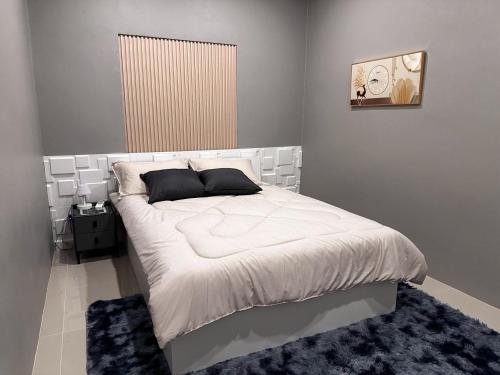 a bedroom with a large bed with white sheets and black pillows at 1-bedroom Modern Cozy near Samui Airport in Ko Samui