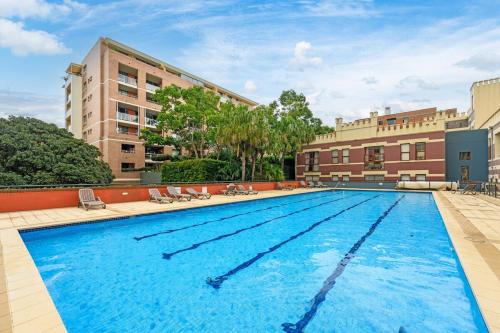 a large swimming pool in front of a building at Redfern 2Br Near CBD Shopping Center with Pool & Gym in Sydney