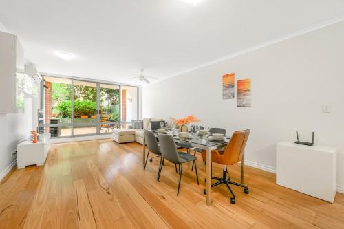 a white living room with a table and chairs at Redfern 2Br Near CBD Shopping Center with Pool & Gym in Sydney