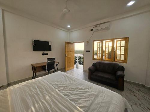 a bedroom with a bed and a chair and a desk at AKR Rooms in Mannar